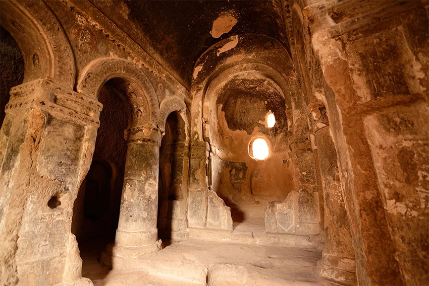 Interior of Selime Cathedral with massive columns and faded frescoes