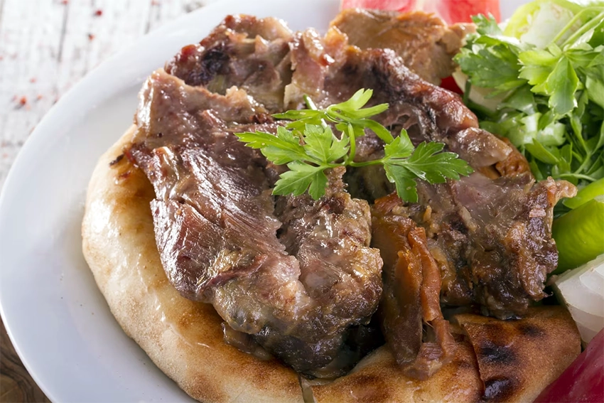 Tandır kebab served with flatbread, onions, and roasted vegetables in Cappadocia